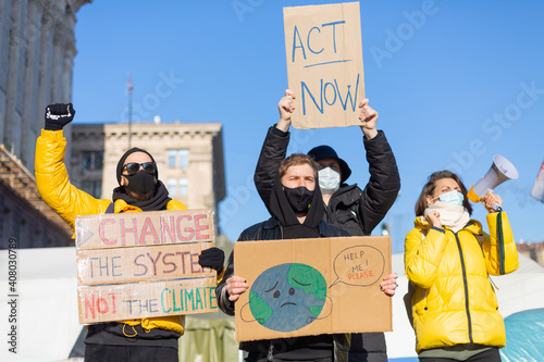 A group of people with banners and a megaphone in hand are protesting in the city square for svae planet clean world act now photo