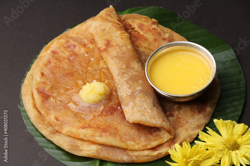 Puran Poli, also known as Holige, is an Indian sweet flatbread from India consumed mostly during Holi festival. Served on banana leaf with pure Ghee over black background. photo