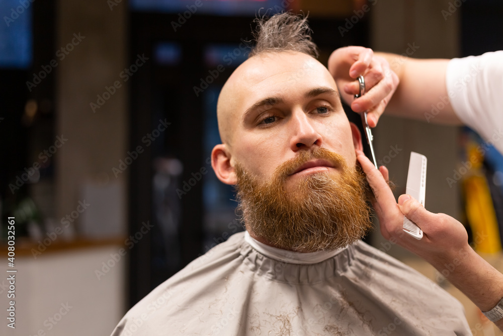 European brutal man with a beard cut in a barbershop European brutal man with a beard cut in a barbershop