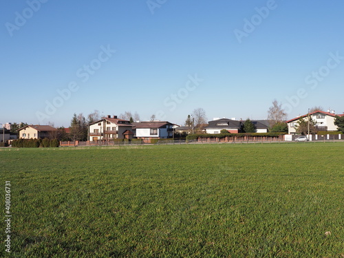 Green field and houses at european Bielsko-Biala city in Silesian district in Poland, clear blue sky in 2020 warm sunny spring day on April.