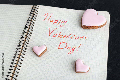 Notebook message Happy Valentines Day and cookies in shape of hearts