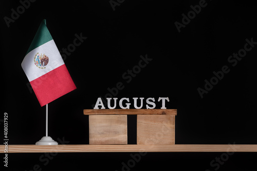 Wooden calendar of August with Mexico flag on black background. Holidays of Mexico in August