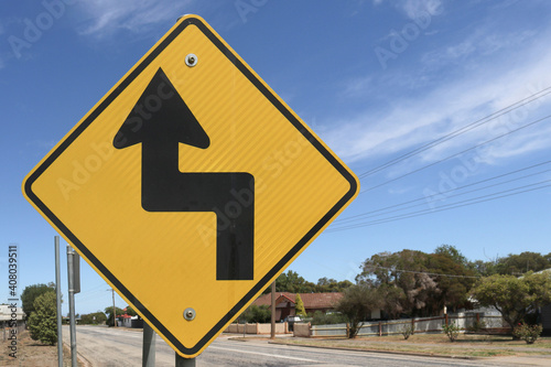 black and yellow road sign warning of Sharp Turn To The Left, Then Sharp Turn To The Right ahead