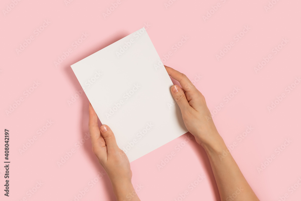Top view of woman hands holding mockup blank paper greeting or invitation card over pink pastel background. Christmas, Valentine, New Year, birthday, winter holidays concept Top view of woman hands holding mockup blank paper greeting or invitation card over pink pastel background. Christmas, Valentine, New Year, birthday, winter holidays concept