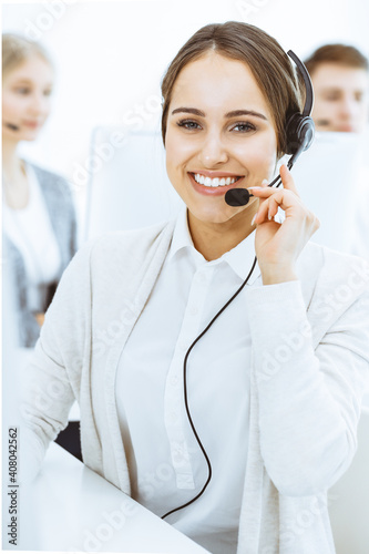 Call center. Group of diverse operators at work. Beautiful woman in headset communicating with customers of telemarketing service. Business concept