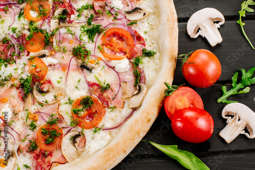 Tasty fresh pizza with ingredients on wooden background photo