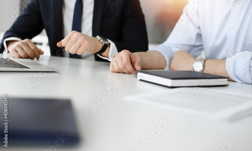 Unknown business people using laptop computer at the desk in modern office. Businessman or male entrepreneur is working with his colleague. Teamwork and partnership concept