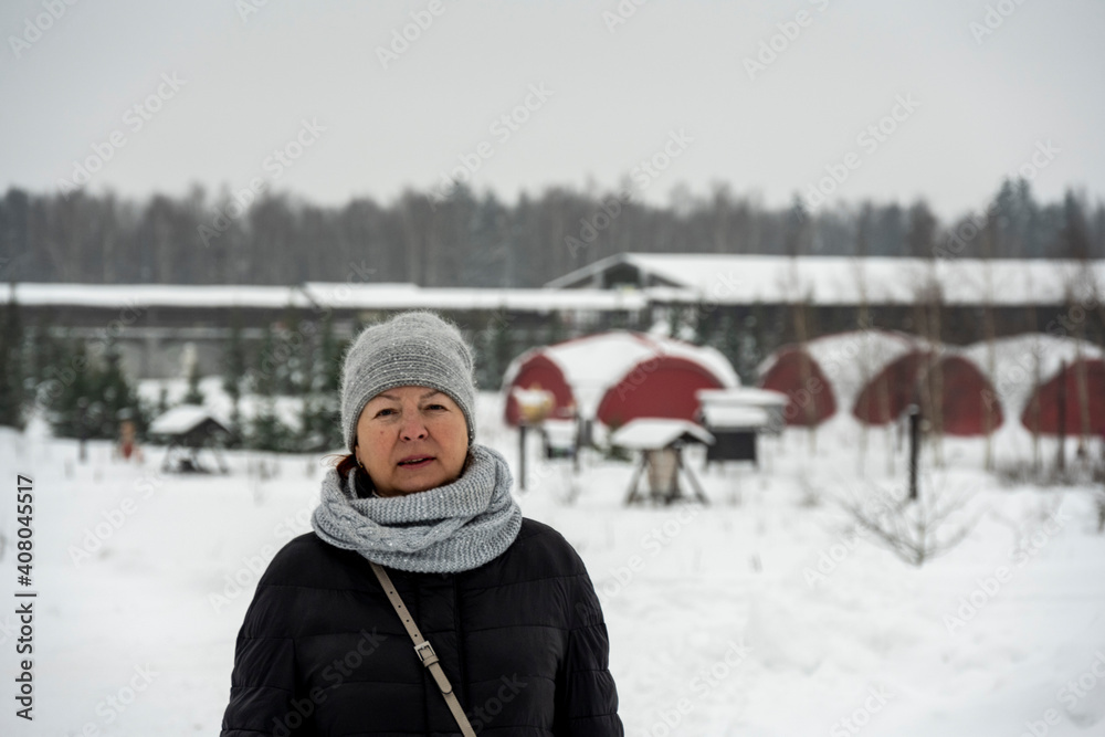 Fototapeta premium woman with a gray hat and a girl in a purple hat on snow-covered paths in the park