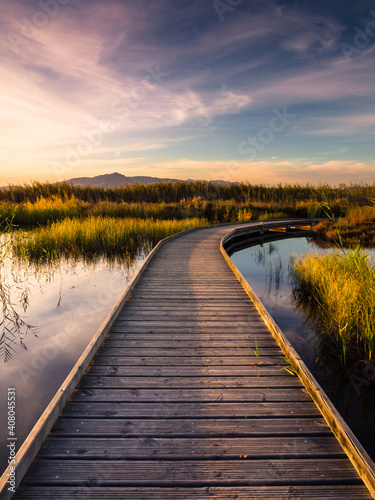 Fototapeta Naklejka Na Ścianę i Meble -  Camino de agua se adentra en laguna con montaña al fondo y puesta de sol