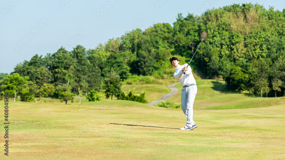Golfer asian man swing and hitting golf ball practice at golf driving range and fairway with bag golf on multiethnic club
