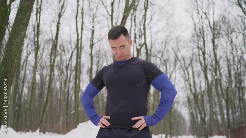Athlete training in winter forest, trail runner, fit man doing exercises in cold weather. A guy in a sports uniform is doing exercises. The athlete does exercises in the winter forest. Athlete training in winter forest, trail runner, fit man doing exercises in cold weather. A guy in a sports uniform is doing exercises. The athlete does exercises in the winter forest.