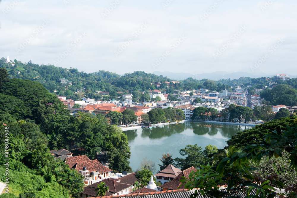 Aerial view of Kandy, a beautiful city at Sri Lanka with buildings, a square lake and many trees.