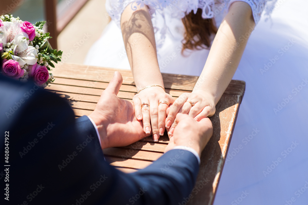 The groom holds the bride's hands while sitting at the table