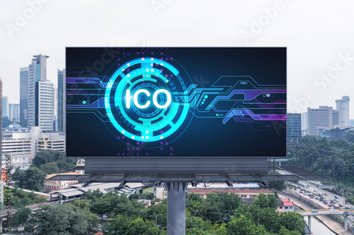 ICO hologram icon on billboard over panorama city view of Kuala Lumpur at day time. KL is the hub of blockchain projects in Malaysia, Asia. The concept of initial coin offering, decentralized finance