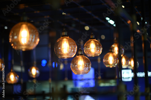 Close up of many modern light gold glass ball hanging lamp with the light on  decorated in the blurred beautiful blue room in a restaurant or coffee shop