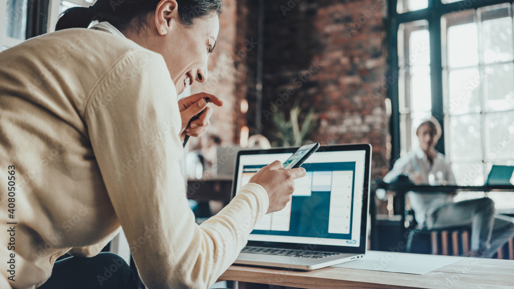 Office business team concept. Smiling happy woman reading good news from the screen of her mobile phone Office business team concept. Smiling happy woman reading good news from the screen of her mobile phone