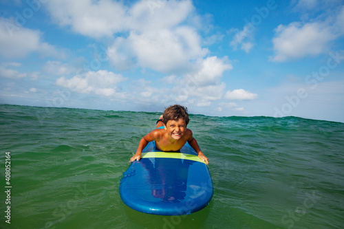 Close portrait of the boy on the surfing board smiling to the camera © Sergey Novikov