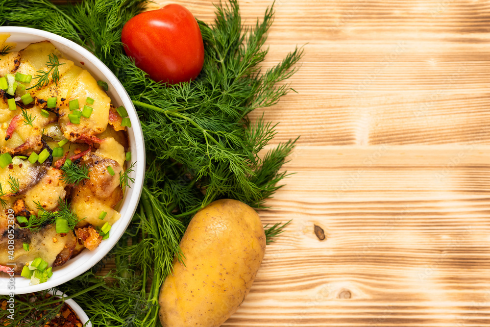 French tartiflette with reblochon cheese and bacon on a wooden background with salad. Copy space. Top view.