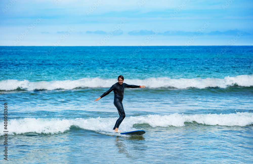 Portrait of the man riding the surfboard in the small waves learning to stand on the board