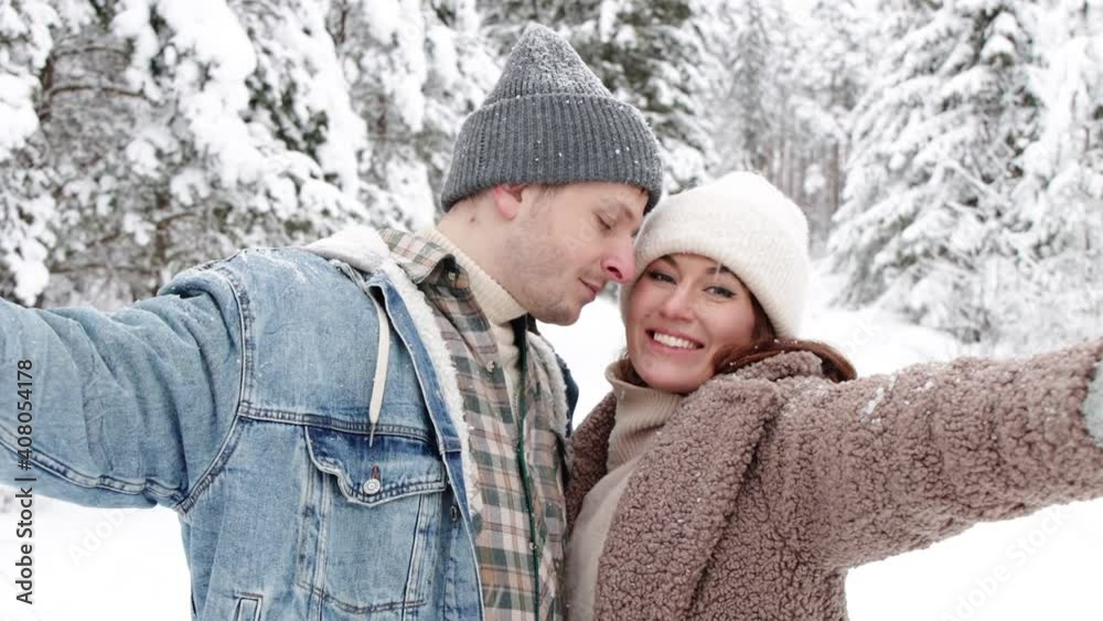 portrait of cute young couple taking selfie photo in winter forest