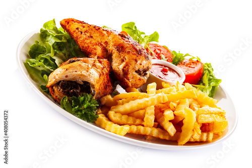 Stuffed chicken fillets, French fries and fresh vegetables
on white background