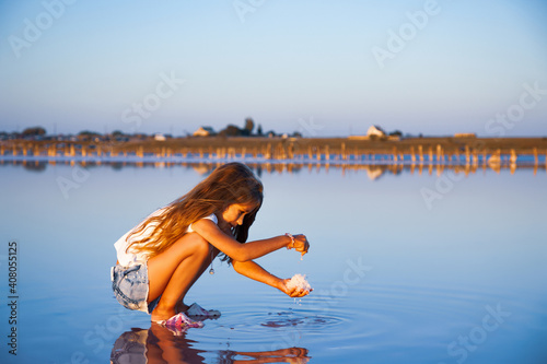 Fototapeta Naklejka Na Ścianę i Meble -  A little beautiful girl with beautiful flowing hair looks at salt in a transparent watery glaze on a transparent background