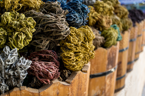 Colored dried seaweed shaped into decorative balls lays in the wooden baskets on the street market © romaset