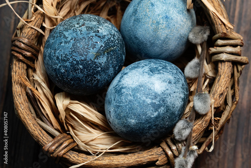 Blue Easter eggs and bouquet of willow flowers on rustic table wood. Naturally Eggs painted with hibiscus with marble stone effect .