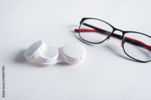Top view of dioptric red-black glasses and white cover for contact lenses on a white background. Concept of medicare.