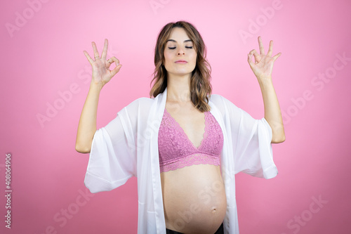 Young beautiful brunette woman pregnant expecting baby over isolated pink background relax and smiling with eyes closed doing meditation gesture with fingers