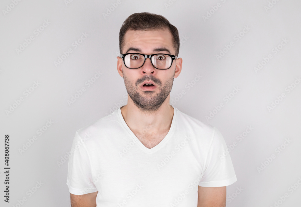 Surprised man with glasses in white t-shirt on gray background Surprised man with glasses in white t-shirt on gray background