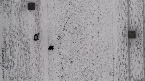 Aerial top down shot, two people walking in winter among many footprints in the snow, drone tracking directly above photo