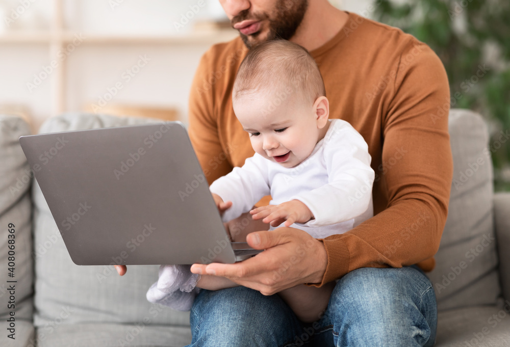 Father Using Laptop Sitting With Baby On Knees At Home Father Using Laptop Sitting With Baby On Knees At Home