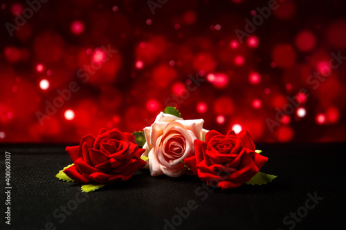 Flowers on a red dramatic blurred background. Two red roses and one white rose lie on the table. Holiday. Romance.
