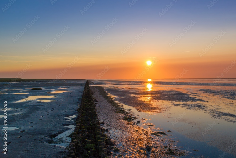 Low tide uncovered a coastal protection (Lahnung) while the sun sets over the wadden sea