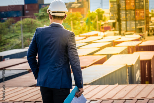 Back of Asian Engineer in Blue suit  standing on top of the container