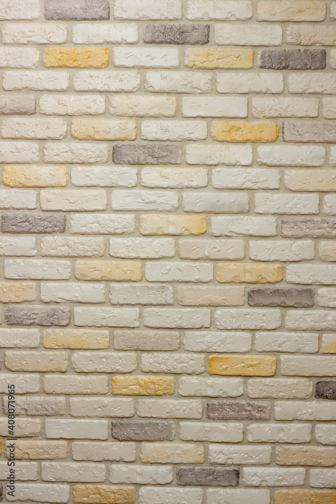 Fototapeta premium Wall with decorative plaster facing bricks following the example of antique tiles in white, yellow and gray. Original background, pattern for graphic works and design
