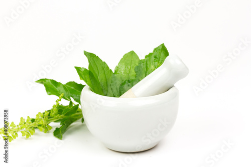 Tulsi or Holy basil leaf in mortar with pestle isolated on white background. Tulsi is used in ayurvedic medicine.
