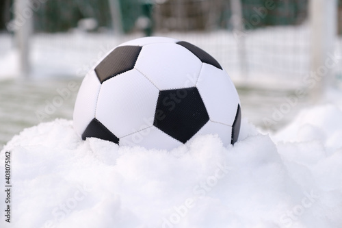 Soccer ball placed on snowdrift near goal in winter on synthetic sports ground © Serhii
