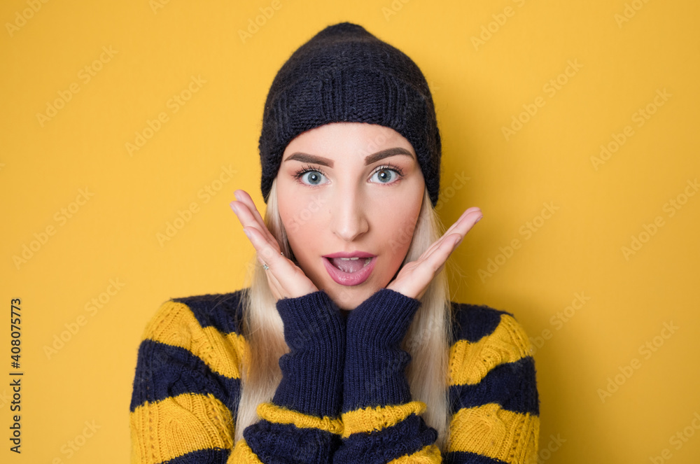 Shocked beautiful woman standing with positive surprised face expressing, model wearing woolen cap and sweater, isolated on yellow background. Crazy pretty girl Shocked beautiful woman standing with positive surprised face expressing, model wearing woolen cap and sweater, isolated on yellow background. Crazy pretty girl