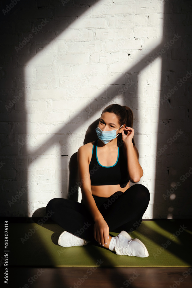 Portrait of fit woman putting on a protective face mask.