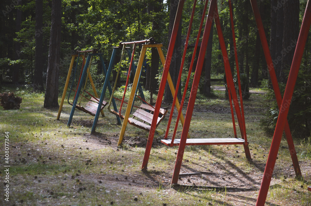 Multi-colored swing among the pine trees in the forest at the recreation center in summer Multi-colored swing among the pine trees in the forest at the recreation center in summer
