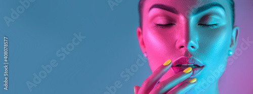 High Fashion model girl in colorful bright UV lights posing in studio, portrait of beautiful woman with trendy make-up and manicure. Art design, colorful make up. Over colourful background photo