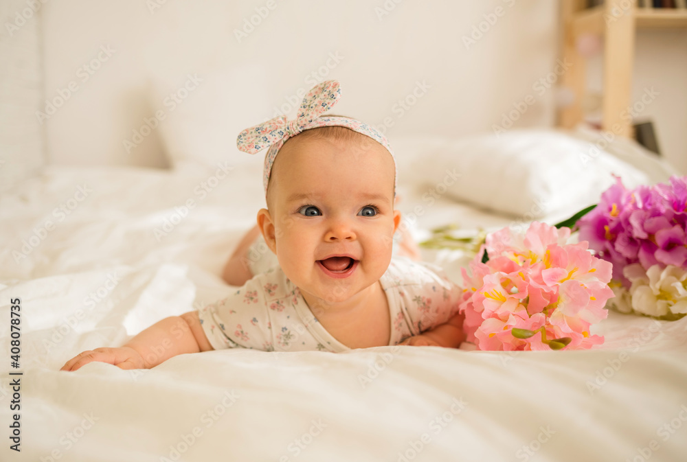 beautiful baby girl lies and smiles with flowers on a bed with a copy of the space beautiful baby girl lies and smiles with flowers on a bed with a copy of the space