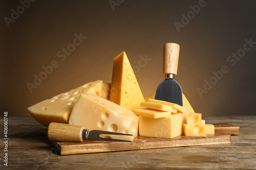 Different sorts of cheese, fork and knife on wooden table