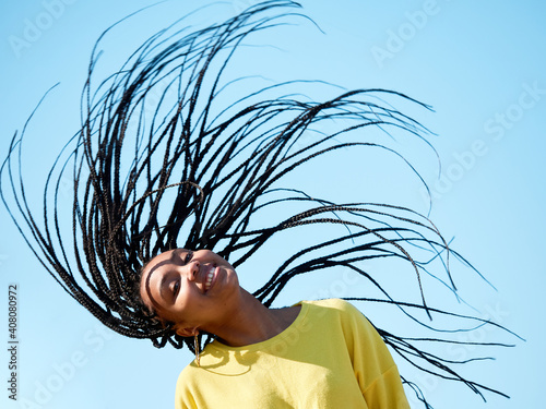 portrait of a young black woman with long hair, african braids or dreadlocks, isolated outdoors