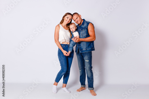 a man and a woman in denim hold a one-year-old baby girl on a white background