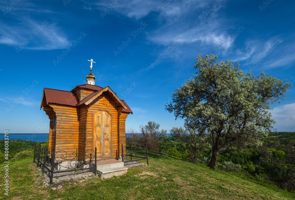 Dnipro river shores summer landscape. Small wooden chapel in Trakhtemyriv historical hilly peninsula on Kaniv water Reservoir Cherkasy Region, Ukraine.