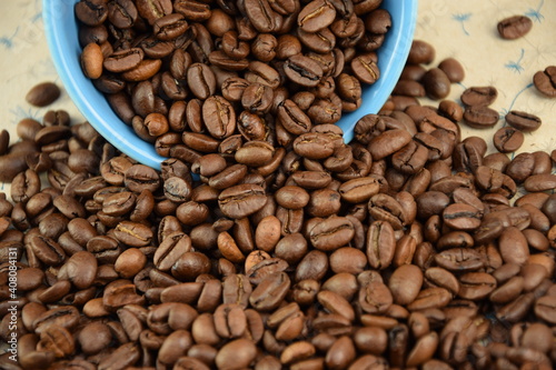 Coffee beans pouring out of a blue bowl Roasted Arabica grain coffee background