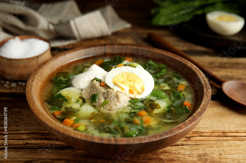 Fotografie Delicious sorrel soup with meat and egg served on  wooden table, closeup